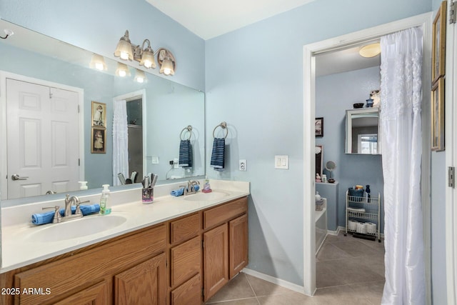 bathroom featuring tile patterned flooring, double vanity, baseboards, and a sink