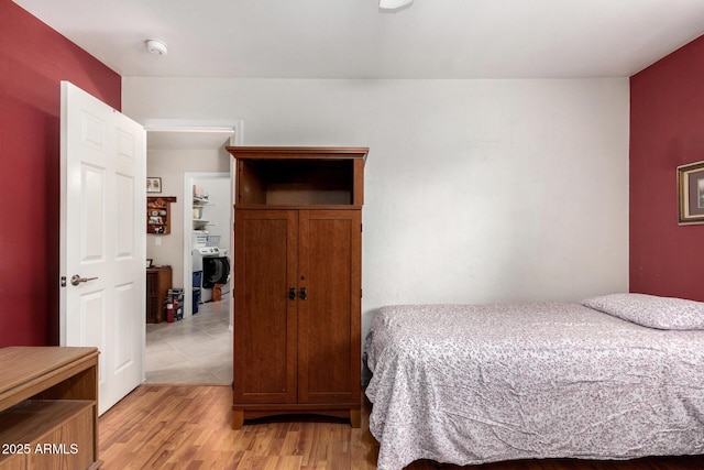 bedroom with washer / dryer and light wood finished floors