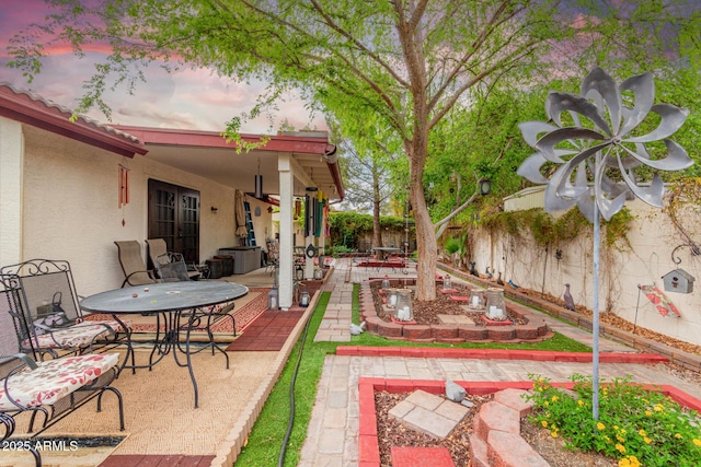 patio terrace at dusk with outdoor dining space and a fenced backyard