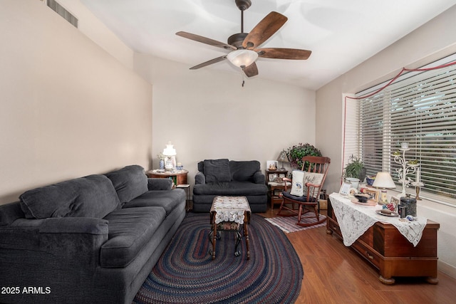 living room featuring ceiling fan, visible vents, lofted ceiling, and wood finished floors