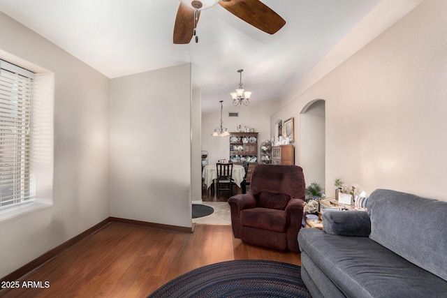 living room with arched walkways, ceiling fan with notable chandelier, baseboards, and wood finished floors