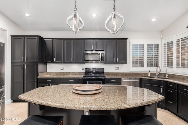 kitchen featuring a sink, a kitchen bar, appliances with stainless steel finishes, and dark cabinetry