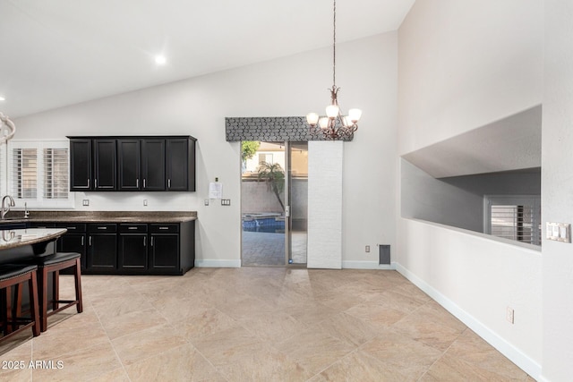 kitchen featuring baseboards, dark cabinetry, pendant lighting, and a sink