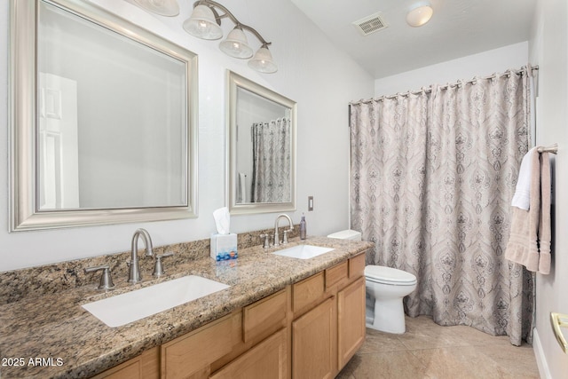 bathroom featuring toilet, double vanity, a sink, and visible vents