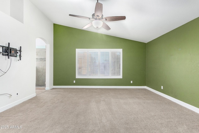 unfurnished room featuring arched walkways, ceiling fan, vaulted ceiling, and light colored carpet