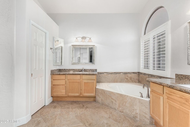 full bath featuring a sink, two vanities, and a garden tub