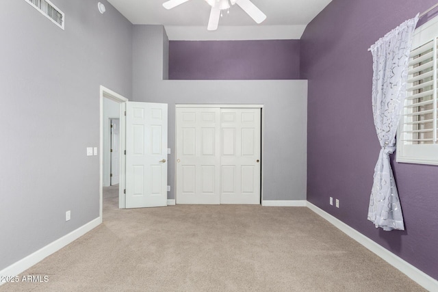 unfurnished bedroom featuring light carpet, baseboards, visible vents, ceiling fan, and high vaulted ceiling