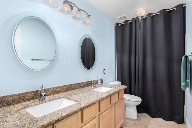 full bath featuring toilet, double vanity, a sink, and visible vents