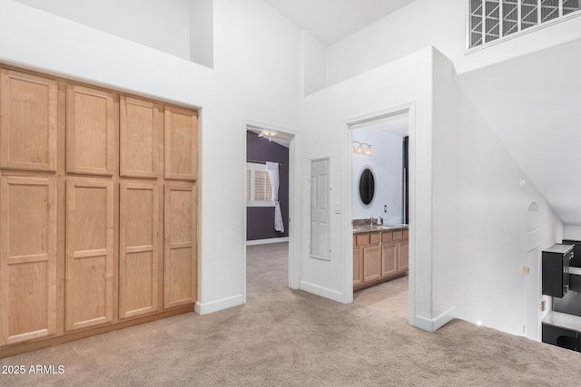 unfurnished bedroom featuring ensuite bathroom, light colored carpet, a sink, visible vents, and baseboards