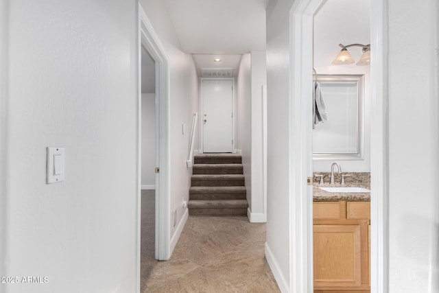 corridor featuring stairs, a sink, and baseboards