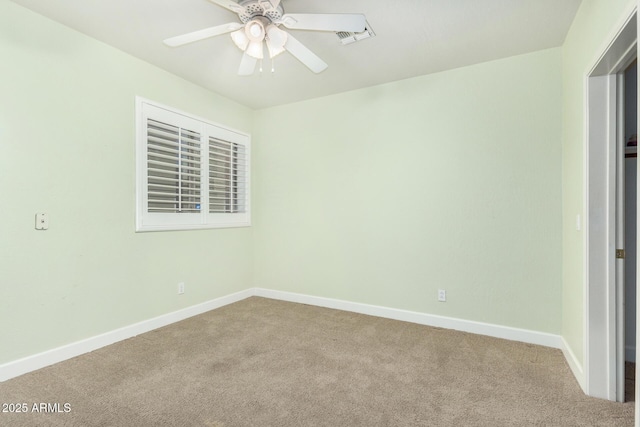 carpeted spare room featuring a ceiling fan and baseboards