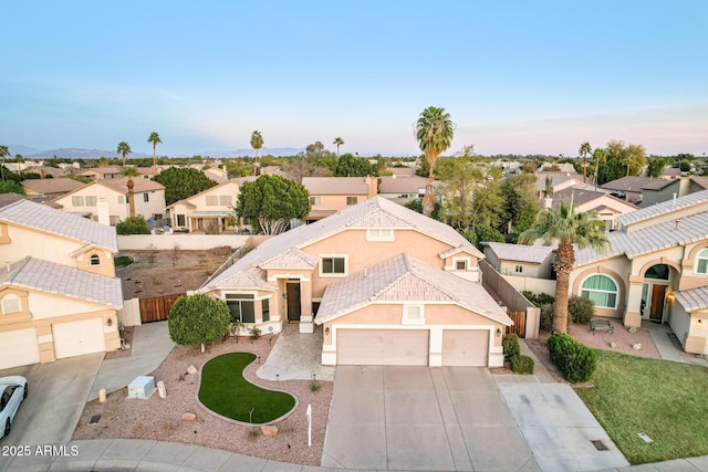 view of front facade with stucco siding, an attached garage, fence, a residential view, and driveway