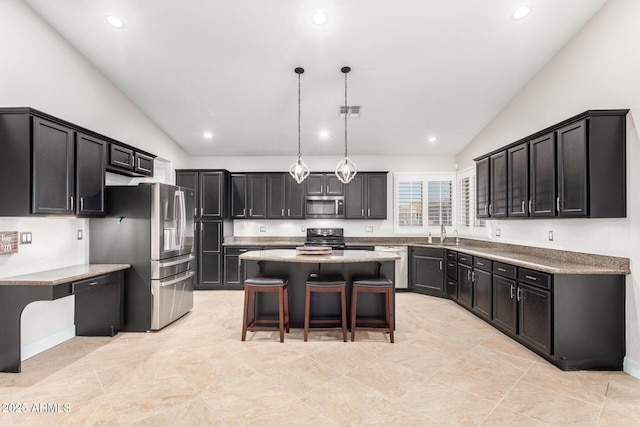 kitchen featuring dark cabinets, a breakfast bar, hanging light fixtures, appliances with stainless steel finishes, and a center island