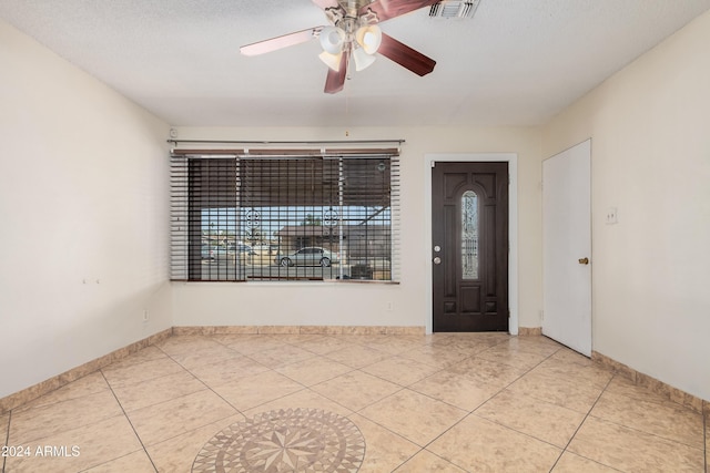 entryway featuring ceiling fan, light tile patterned floors, and a textured ceiling