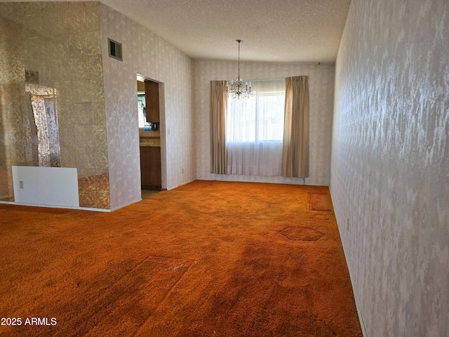 carpeted spare room featuring a chandelier and a textured ceiling