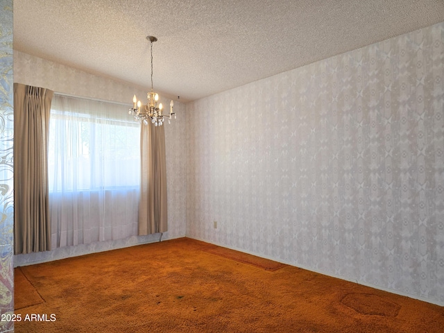 spare room featuring an inviting chandelier, carpet floors, and a textured ceiling