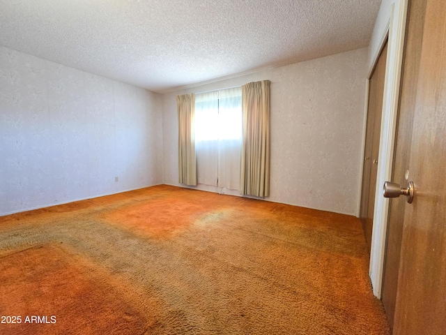 unfurnished room featuring a textured ceiling and light colored carpet