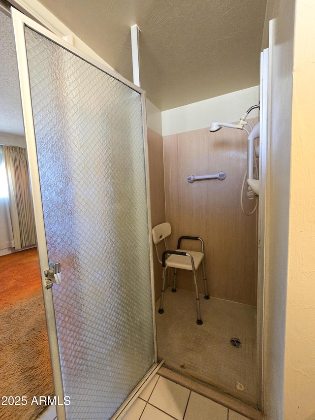 bathroom with a textured ceiling, walk in shower, and tile patterned flooring