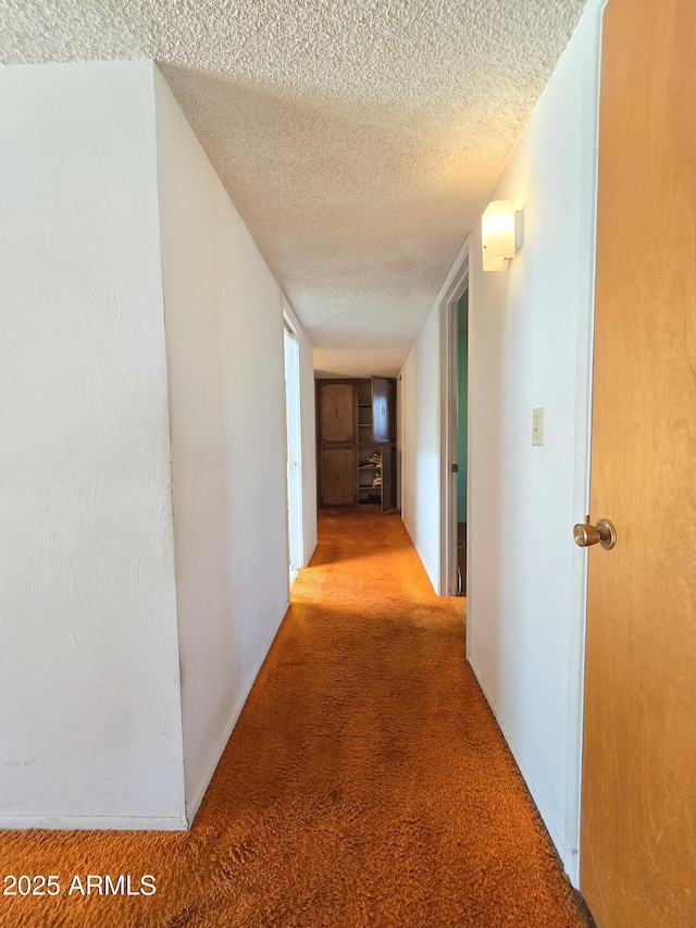 hallway with a textured ceiling and light carpet