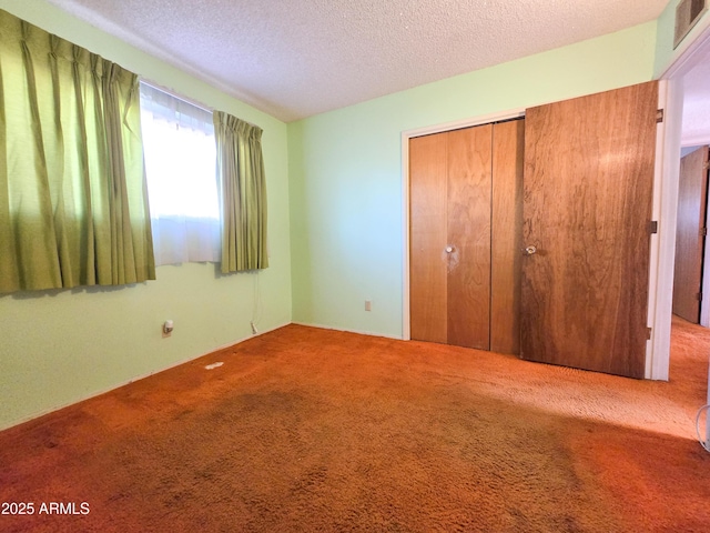 unfurnished bedroom with carpet floors, a textured ceiling, and a closet