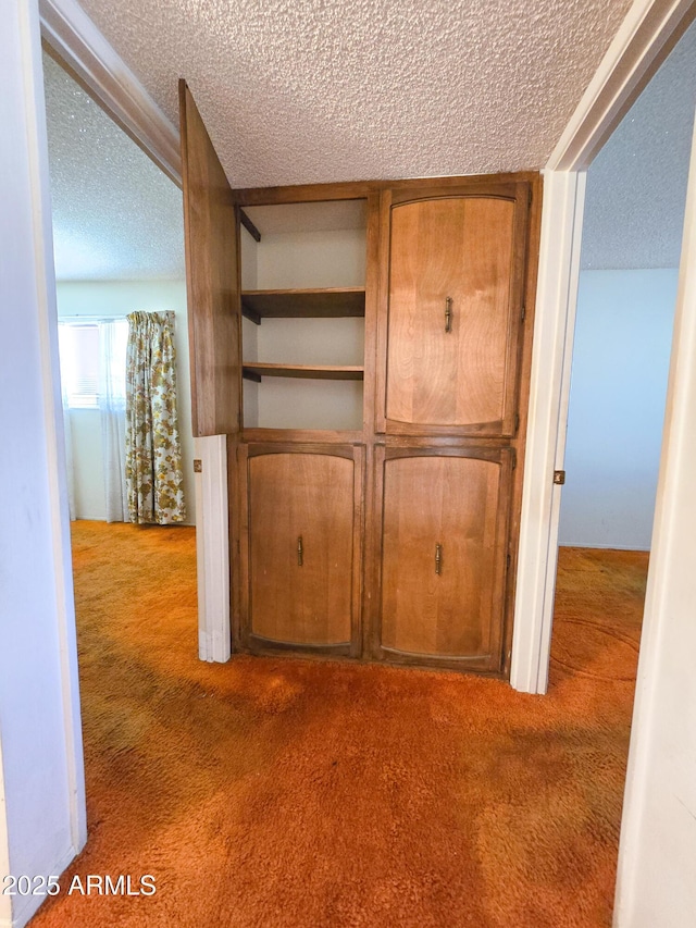 hallway featuring dark colored carpet and a textured ceiling