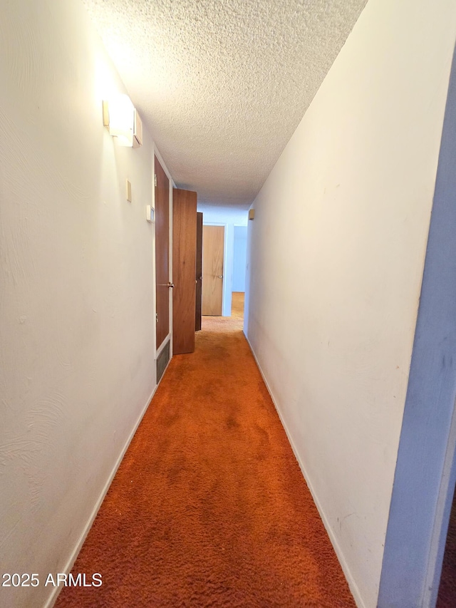 hallway with a textured ceiling and carpet flooring