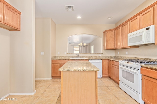 kitchen featuring light stone counters, white appliances, a kitchen island, sink, and a notable chandelier