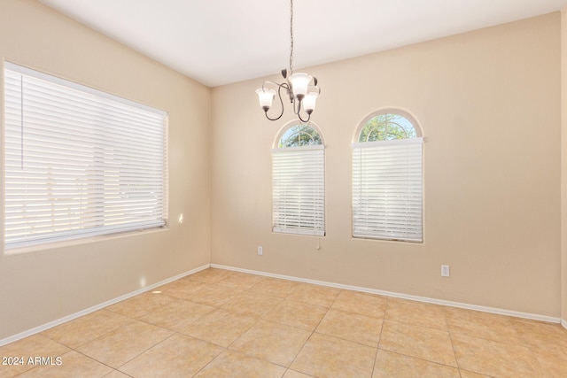 spare room with a chandelier and light tile patterned flooring