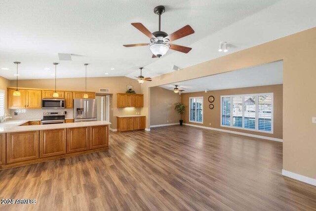 kitchen featuring decorative light fixtures, stainless steel appliances, sink, dark hardwood / wood-style floors, and vaulted ceiling