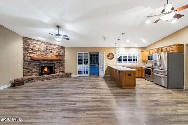 kitchen with wood-type flooring, kitchen peninsula, stainless steel appliances, and hanging light fixtures