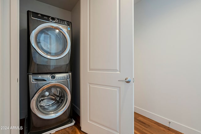 washroom featuring wood-type flooring and stacked washer / drying machine