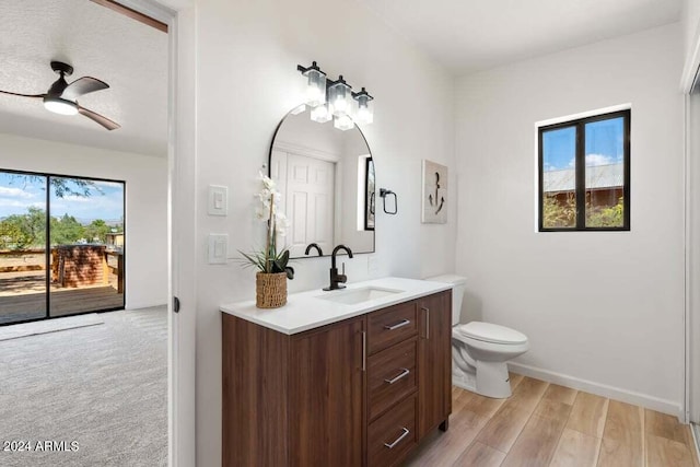 bathroom featuring ceiling fan, toilet, vanity, and wood-type flooring