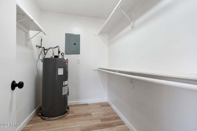 spacious closet with electric water heater, electric panel, and hardwood / wood-style floors