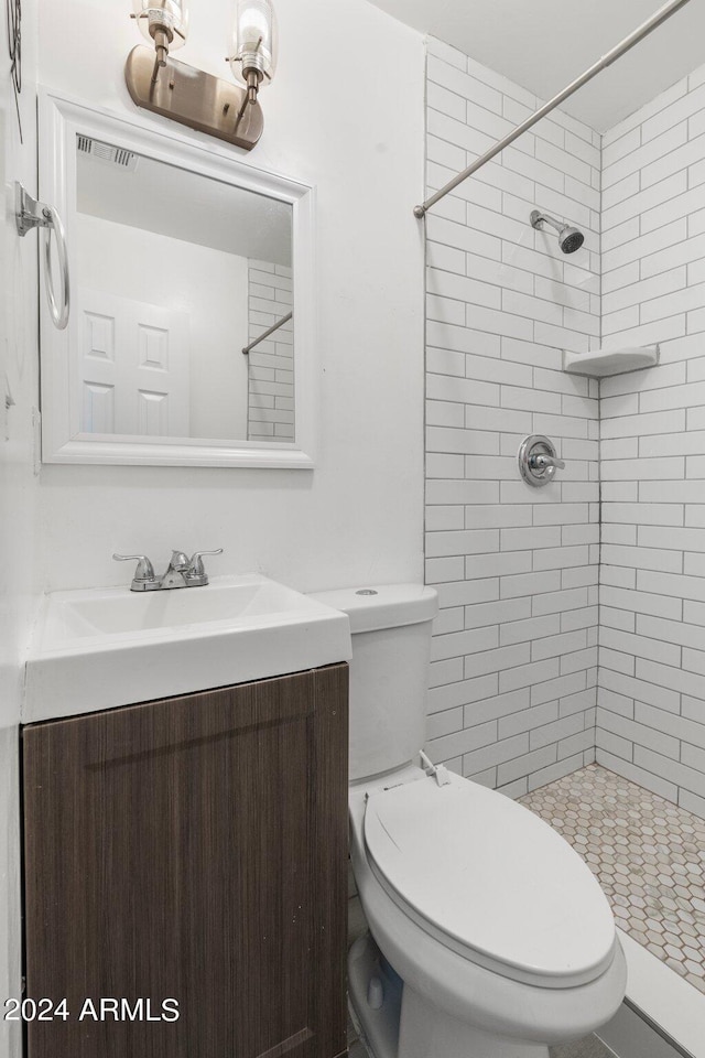 bathroom with tiled shower, vanity, and toilet