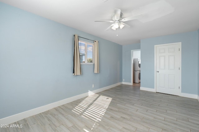 unfurnished room with stacked washer and dryer, ceiling fan, and light hardwood / wood-style flooring