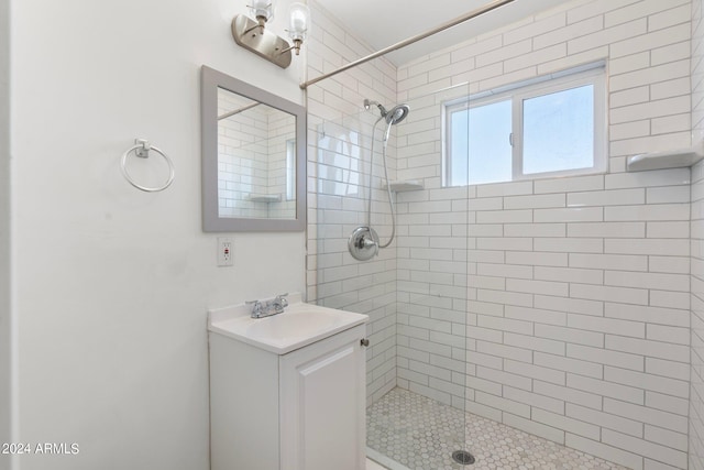 bathroom with a tile shower and vanity