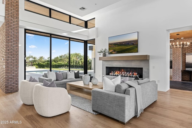 7341 E Sunnyside Dr, Scottsdale, AZ 85260 - living area with a warm lit fireplace, wood finished floors, a high ceiling, a chandelier, and expansive windows