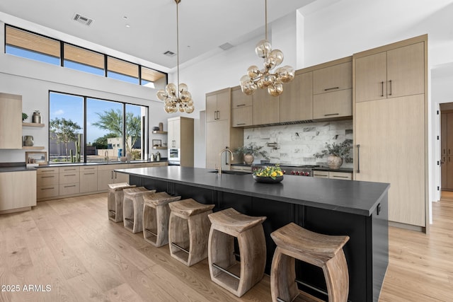 7341 E Sunnyside Dr, Scottsdale, AZ 85260 - kitchen featuring dark countertops, a towering ceiling, open shelves, a sink, and backsplash