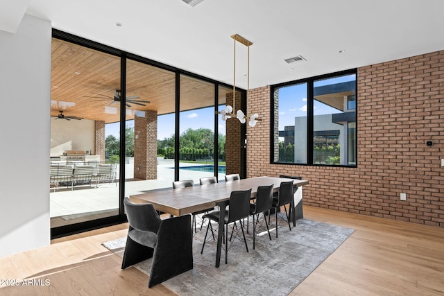7341 E Sunnyside Dr, Scottsdale, AZ 85260 - dining area with brick wall, a wall of windows, and wood finished floors