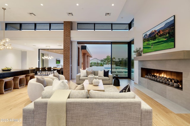 7341 E Sunnyside Dr, Scottsdale, AZ 85260 - living room featuring a chandelier, wood finished floors, a fireplace with flush hearth, recessed lighting, and a high ceiling