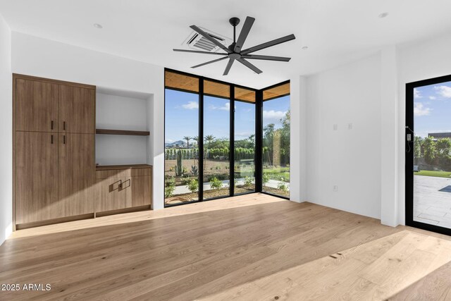 7341 E Sunnyside Dr, Scottsdale, AZ 85260 - unfurnished living room with light wood-type flooring, a ceiling fan, expansive windows, and built in shelves