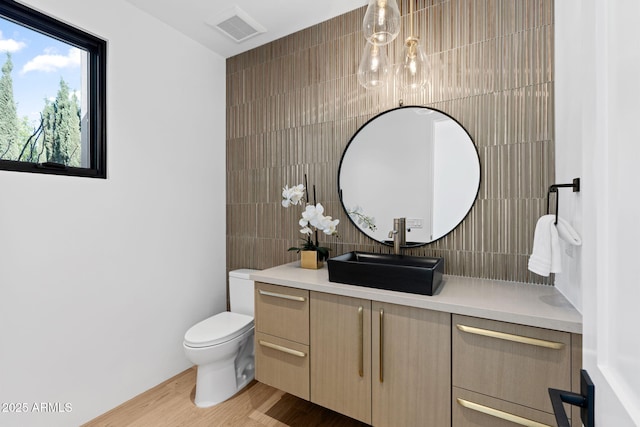 7341 E Sunnyside Dr, Scottsdale, AZ 85260 - bathroom with vanity, toilet, wood finished floors, tile walls, and decorative backsplash