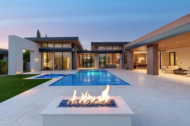 7341 E Sunnyside Dr, Scottsdale, AZ 85260 - back of property at dusk featuring an outdoor living space with a fire pit, a patio area, and a pool with connected hot tub
