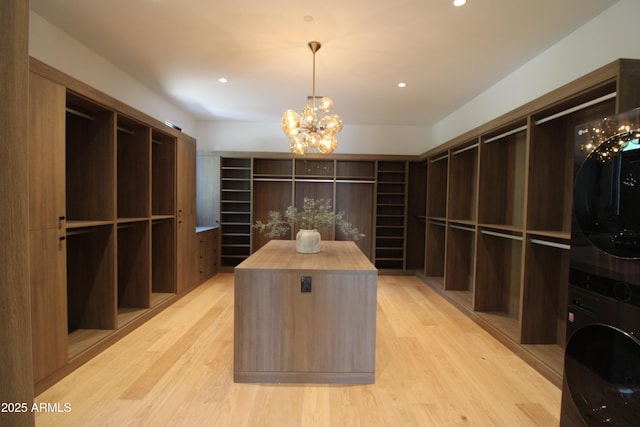 7341 E Sunnyside Dr, Scottsdale, AZ 85260 - walk in closet with stacked washer / dryer, a chandelier, and light wood-style floors