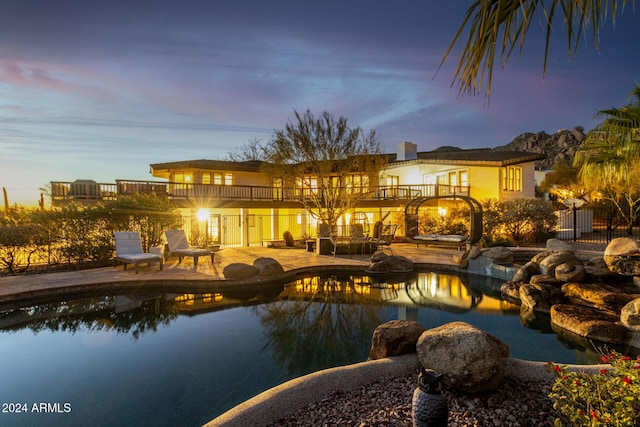 rear view of house with a patio area, an outdoor pool, a balcony, and fence