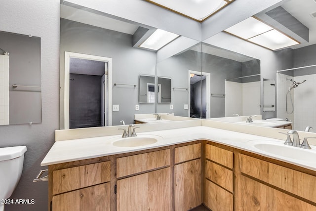 bathroom with a sink, tiled shower, and toilet