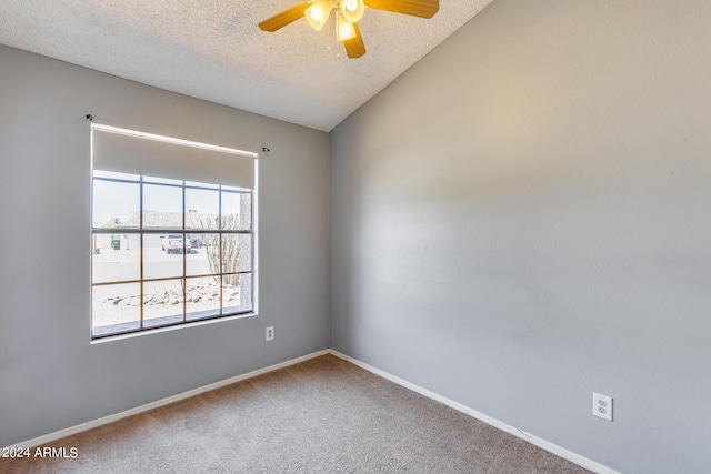 carpeted empty room featuring baseboards, a textured ceiling, ceiling fan, and vaulted ceiling