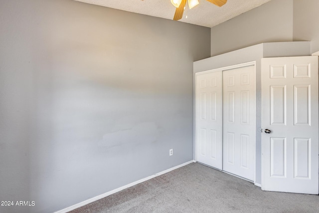 unfurnished bedroom featuring a ceiling fan, a textured ceiling, a closet, carpet floors, and baseboards