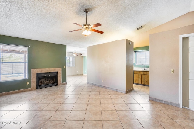 unfurnished living room with lofted ceiling, light tile patterned floors, visible vents, and a tile fireplace