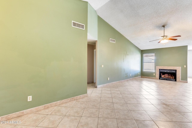 unfurnished living room with visible vents, ceiling fan, a tiled fireplace, light tile patterned floors, and a textured ceiling